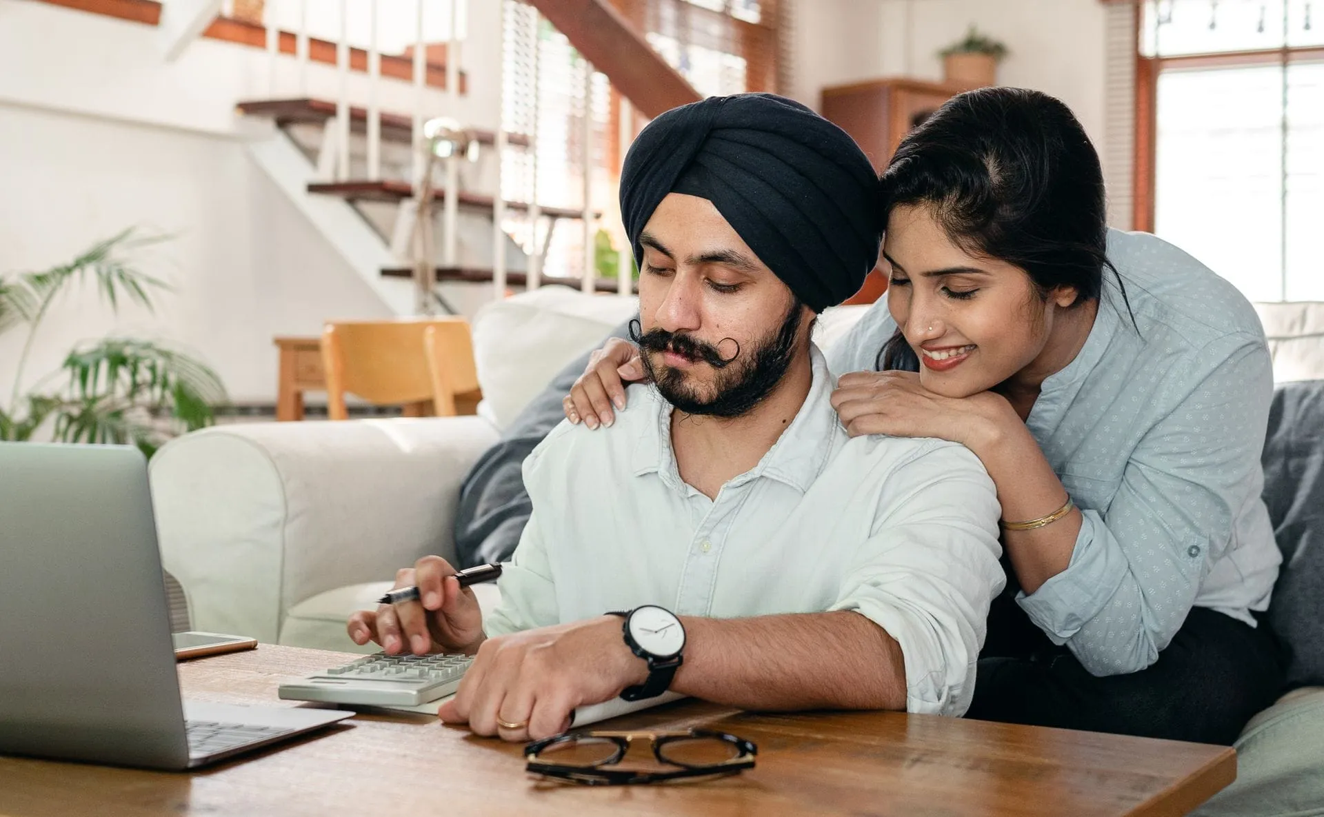 Indian couple reviewing business accounts with a laptop and calculator at home